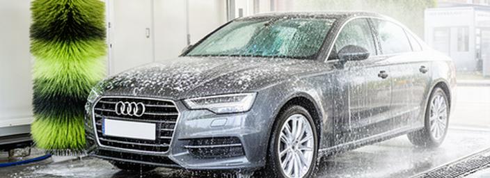 Een glanzende auto die professioneel gewassen wordt in een carwash in Wavre, met zachte schuimborstels en helder water dat over de lak stroomt